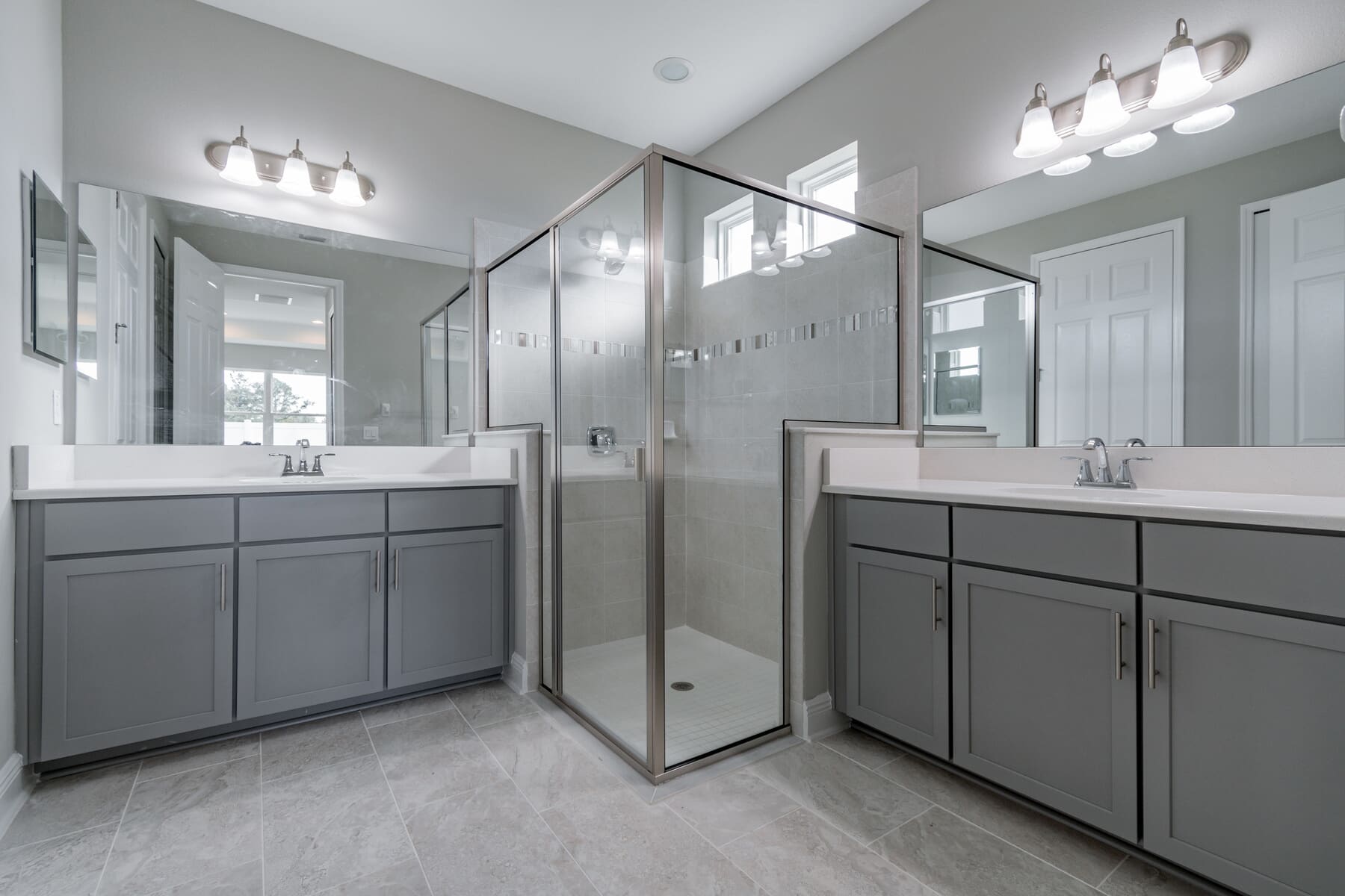 L-Shaped Bathroom With Two Vanities and Matching Lighting