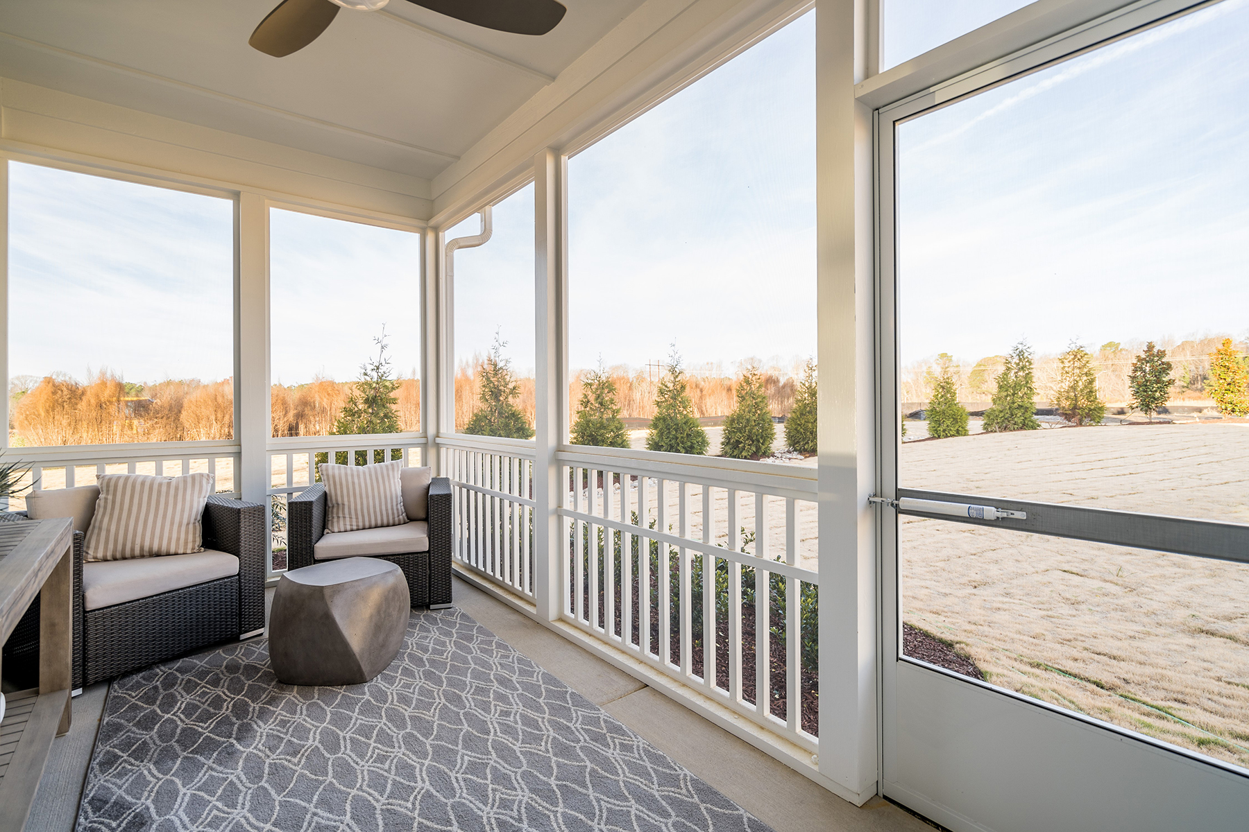 White Screened Porch With Gray Accent Rug And Chairs