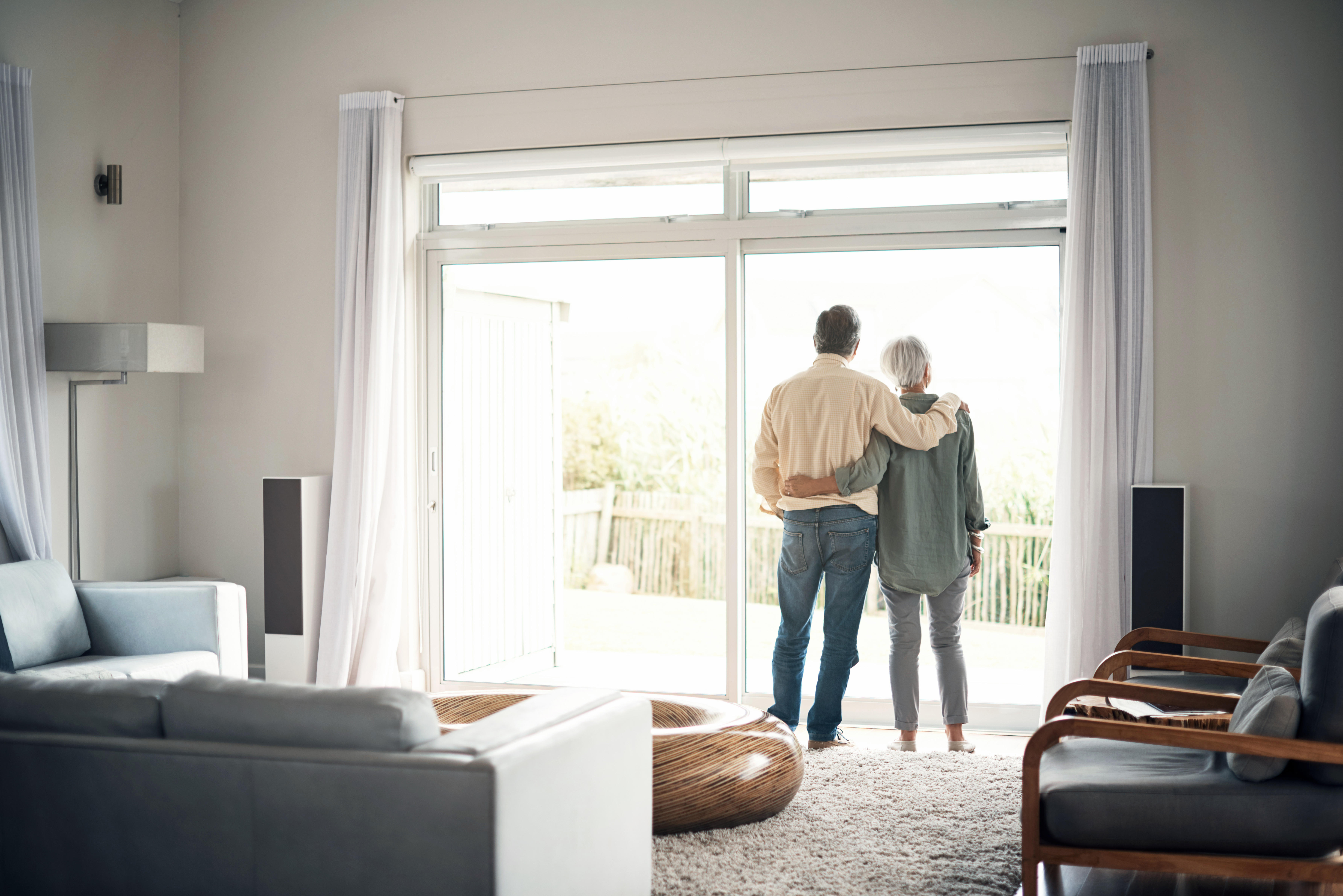 Senior Couple Looking Out Back Door of Home