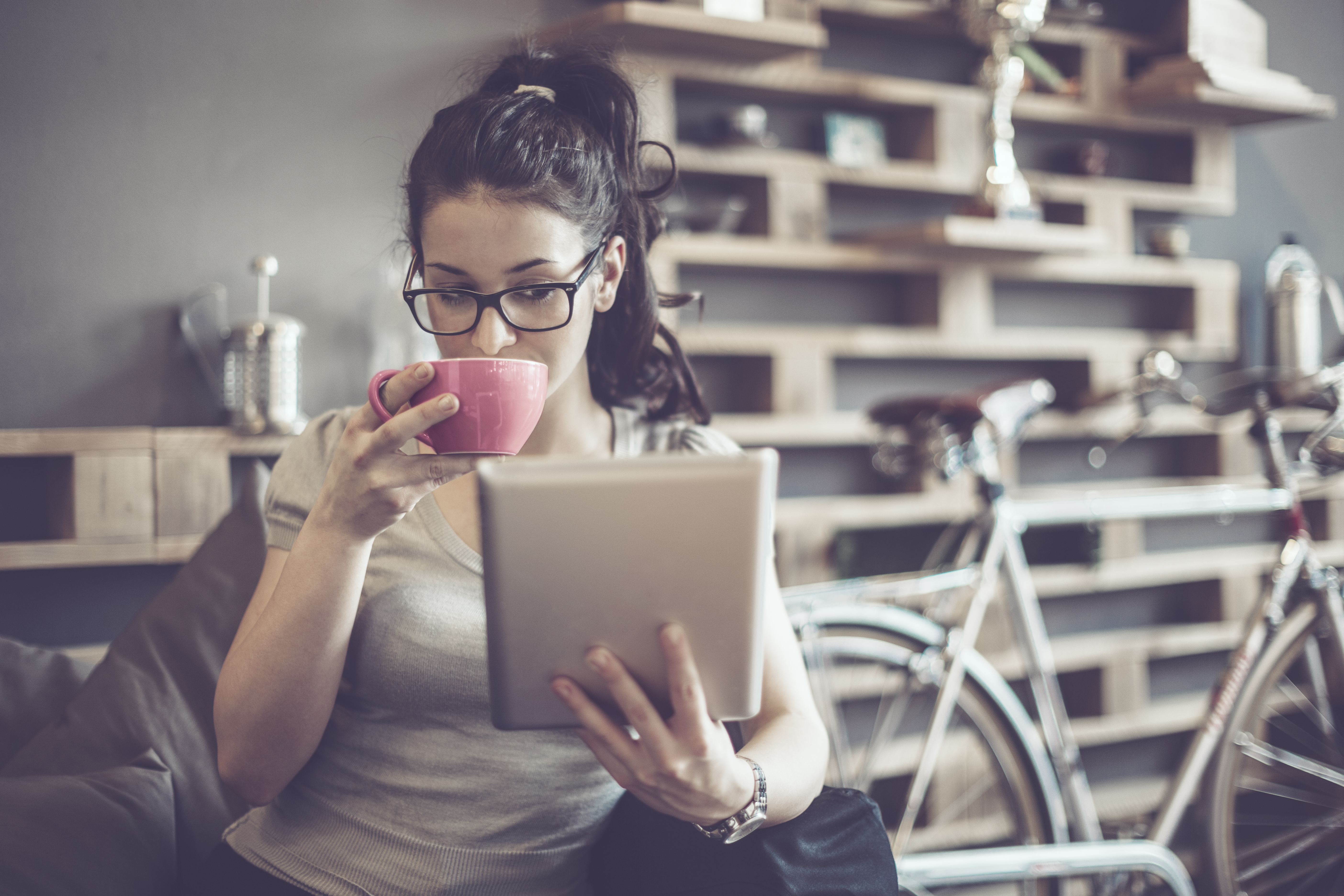 Woman Reading on Tablet and Drinking Coffee