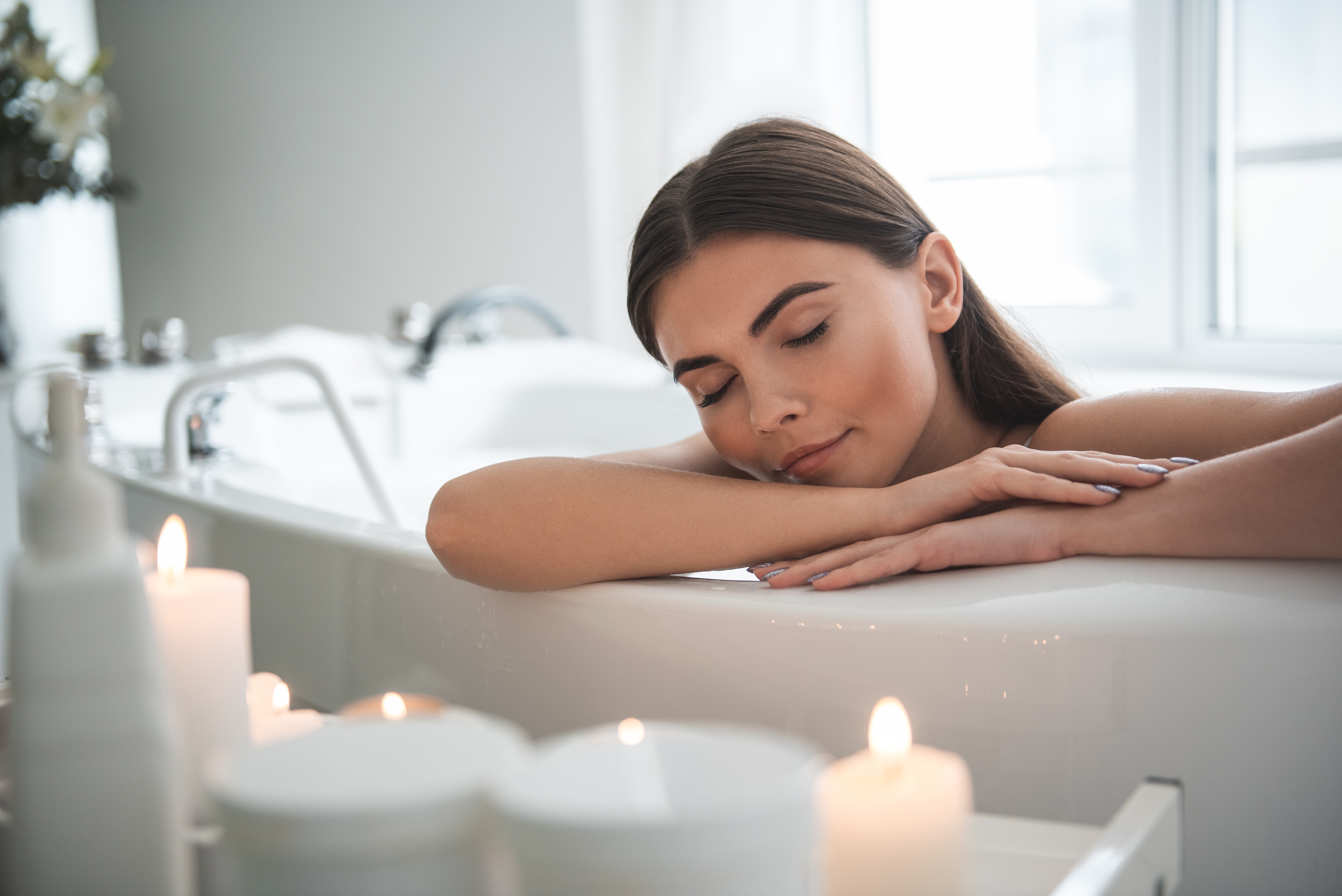 Woman Relaxing in Bathtub With Candles Burning Nearby