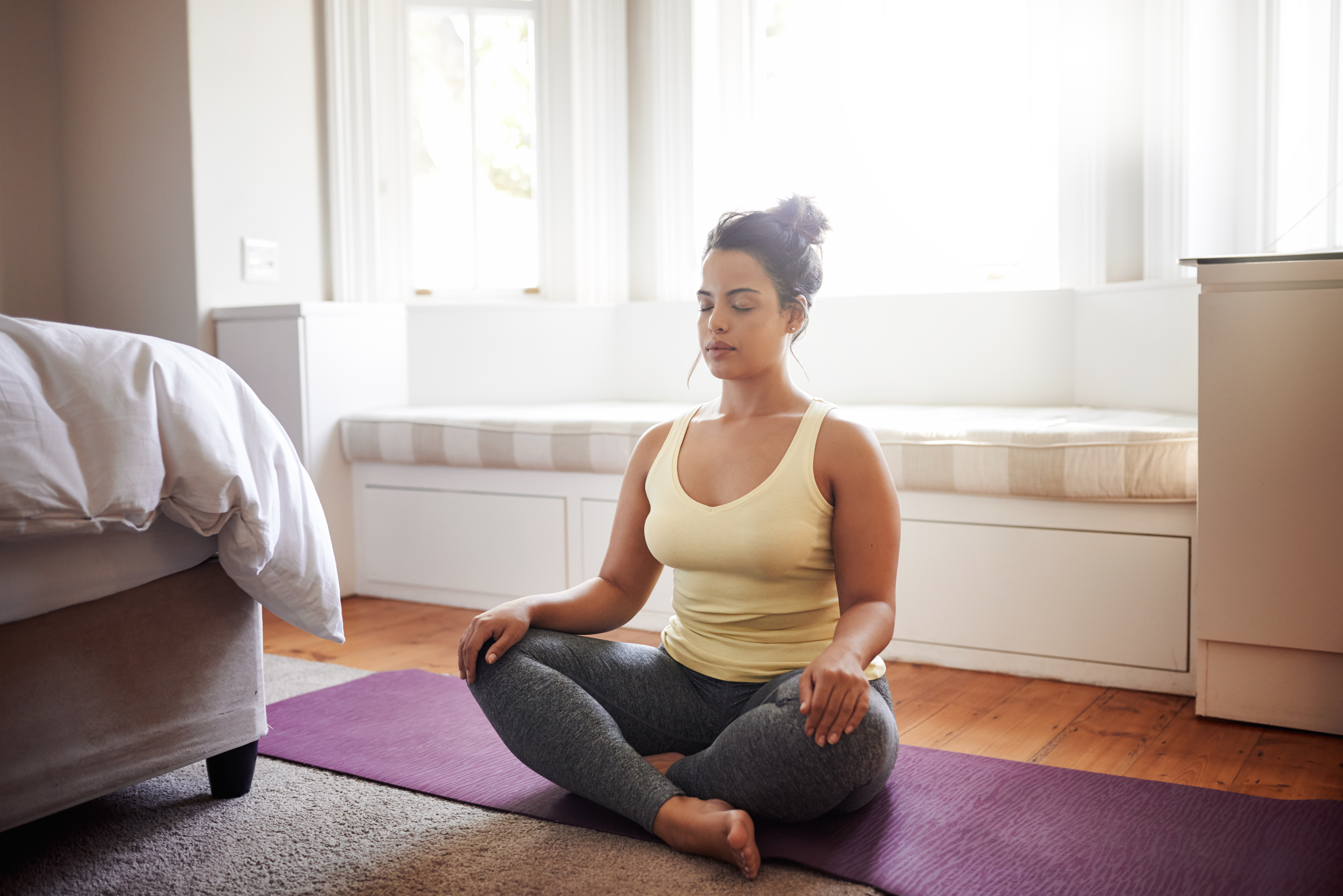 Woman Sitting on Yoga Mat in Bedroom Doing Sitting Yoga Pose