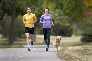 Couple running in a park with a dog