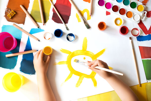 Close up of child painting a sun on paper