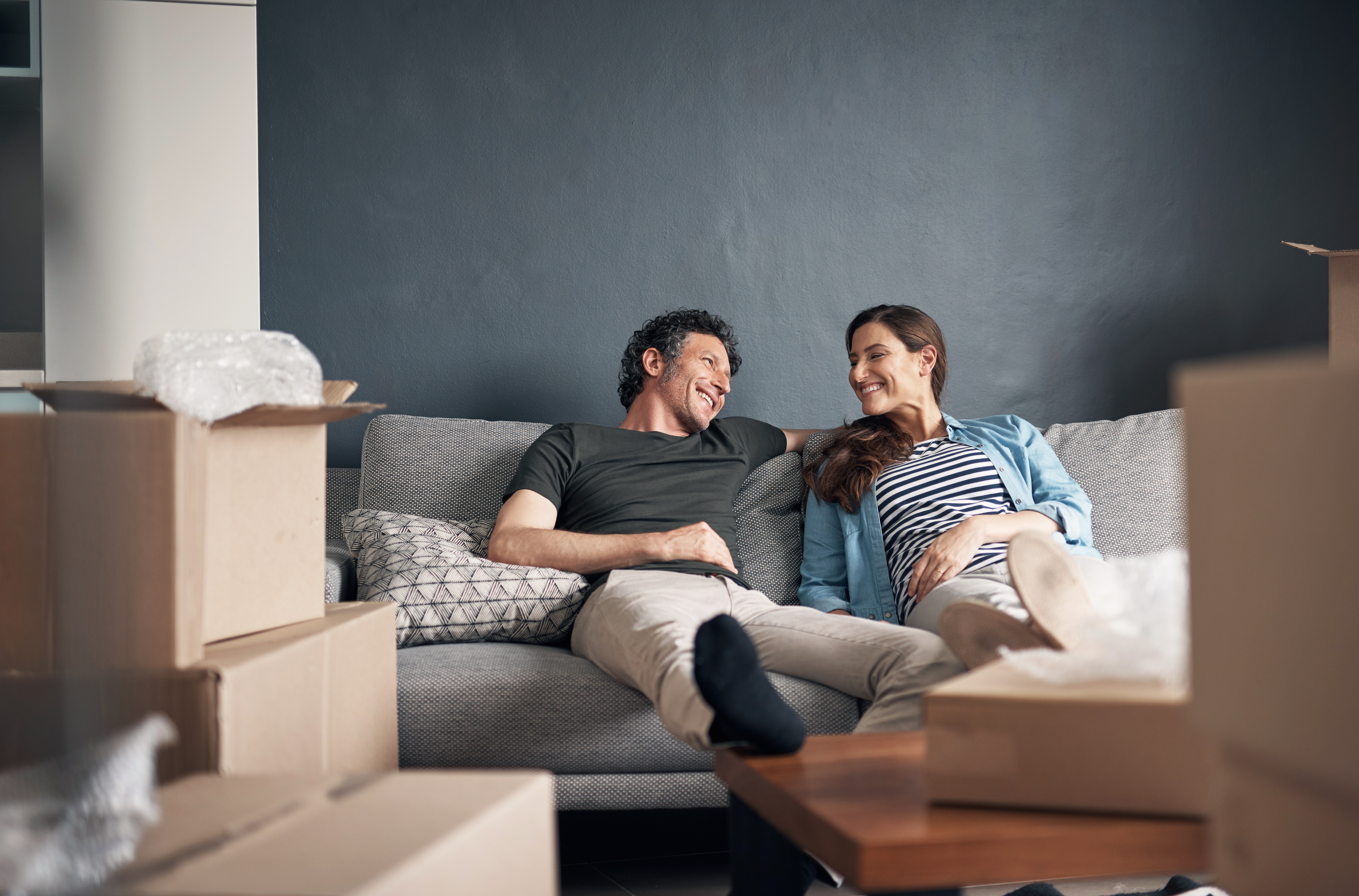 Couple Sitting on Couch With Moving Boxes All Around