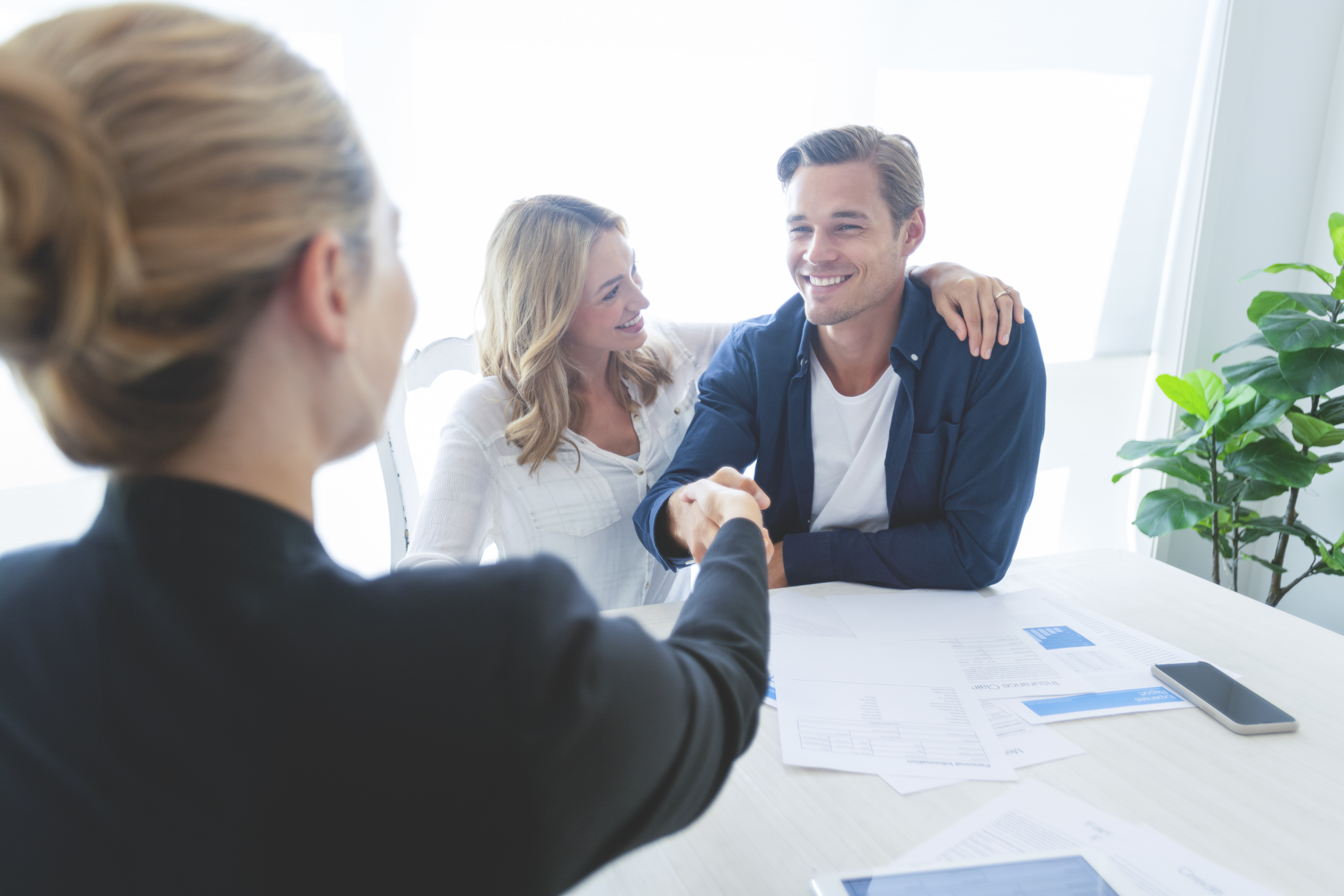 Young couple sitting at a table shaking hands with an employee