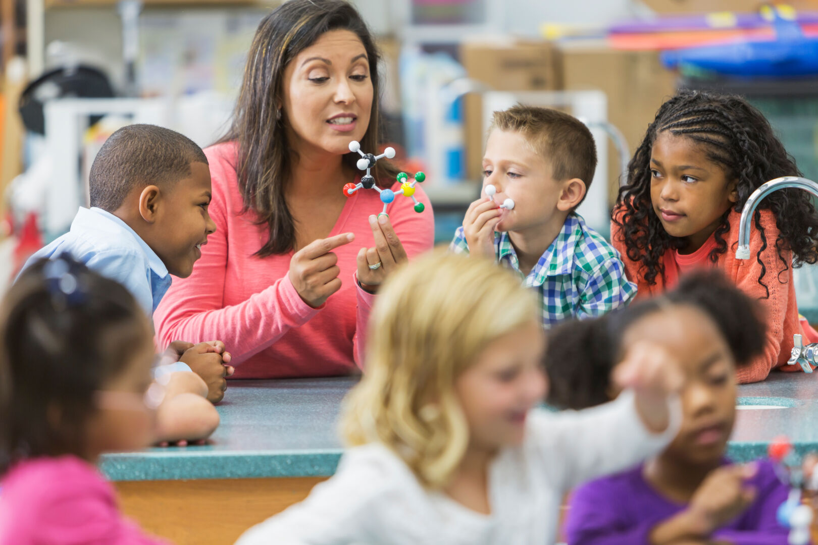 [elementary teacher showing students a science model]