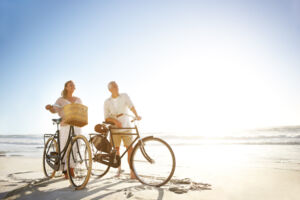Older couple on bikes on a beach