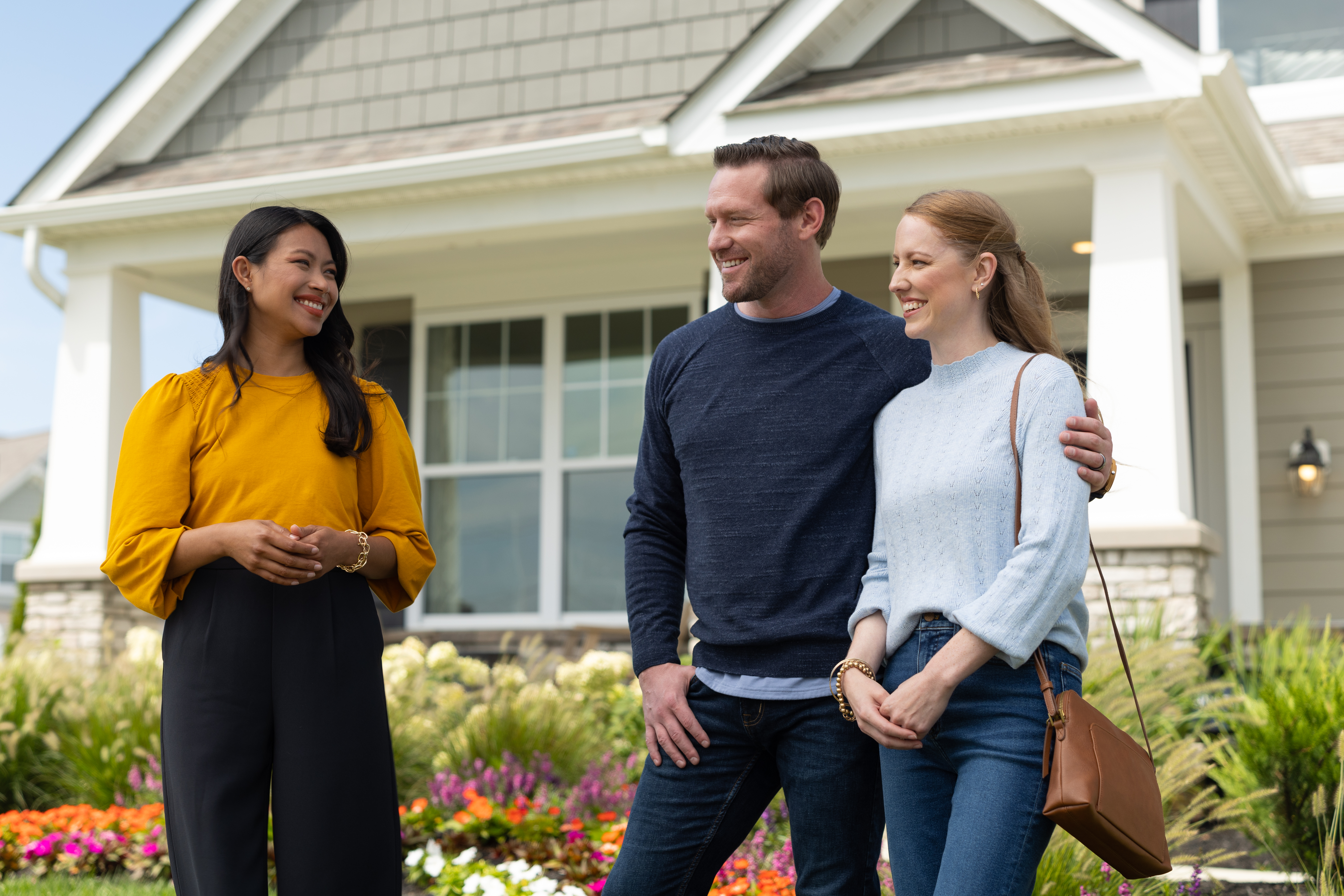 couple standing with a New Home Consultant in front of a home