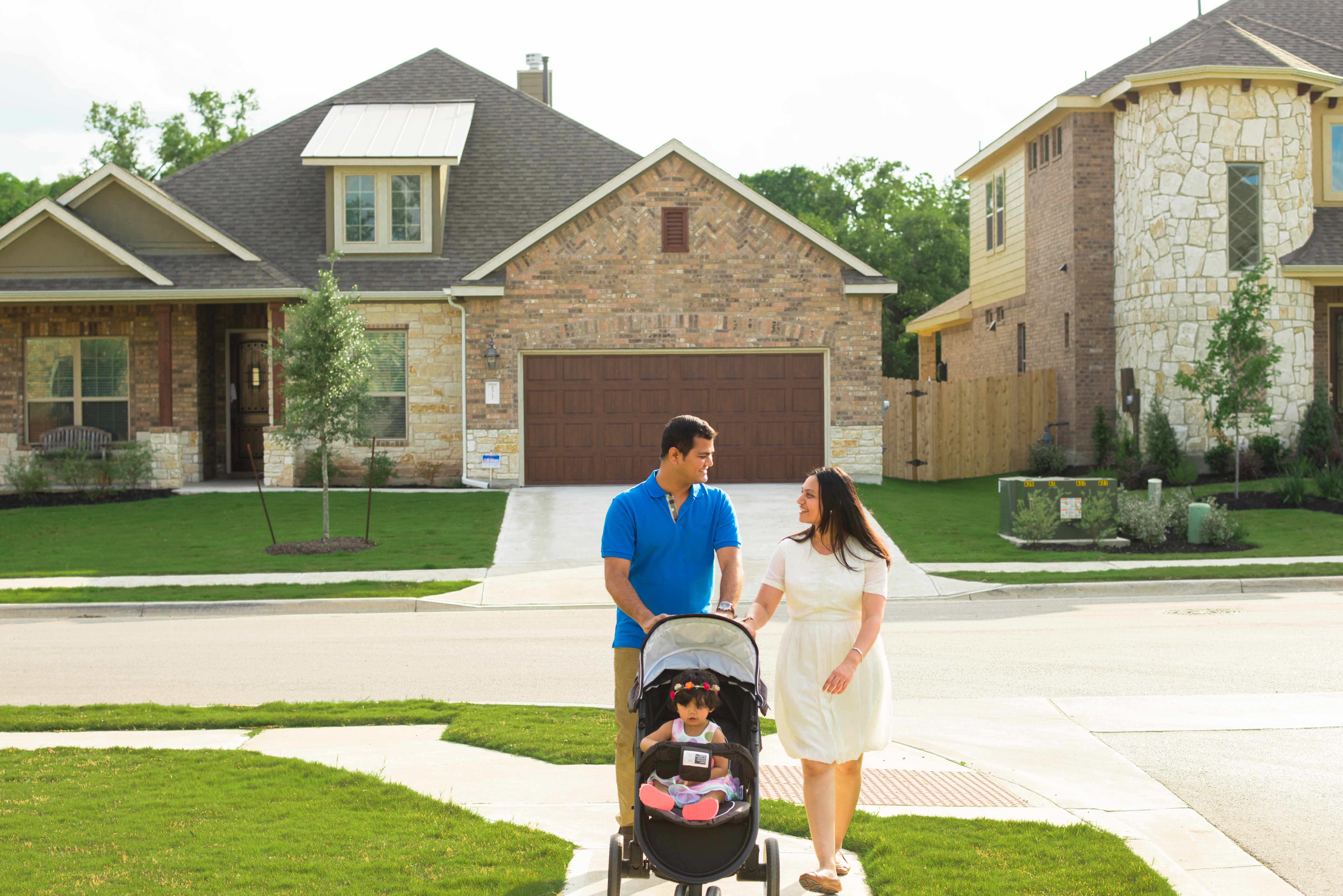 Couple Pushing Their Child In a Stroller Through a Neighborhood