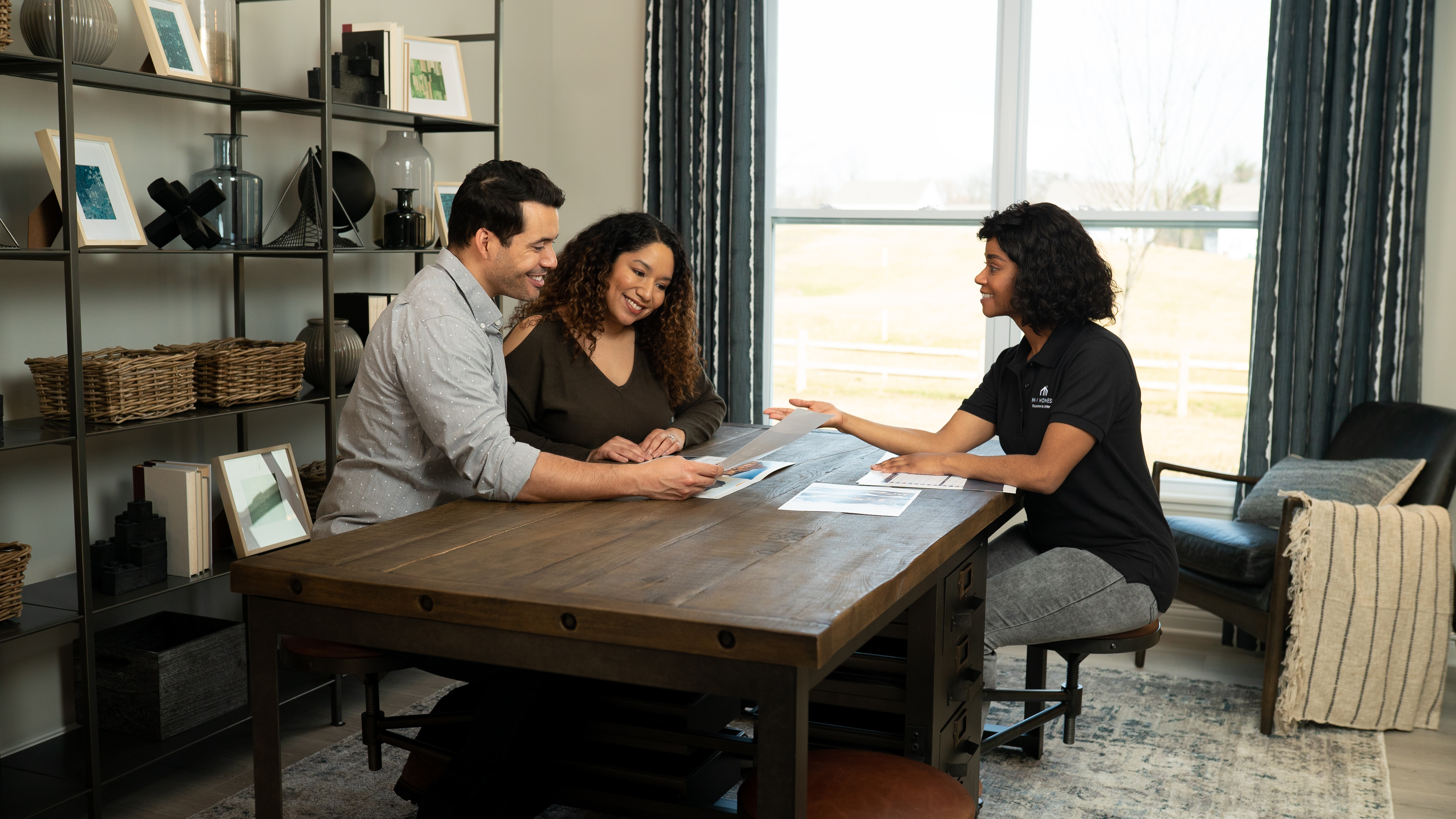 Couple Sitting At Desk With Employee Looking at Paperwork