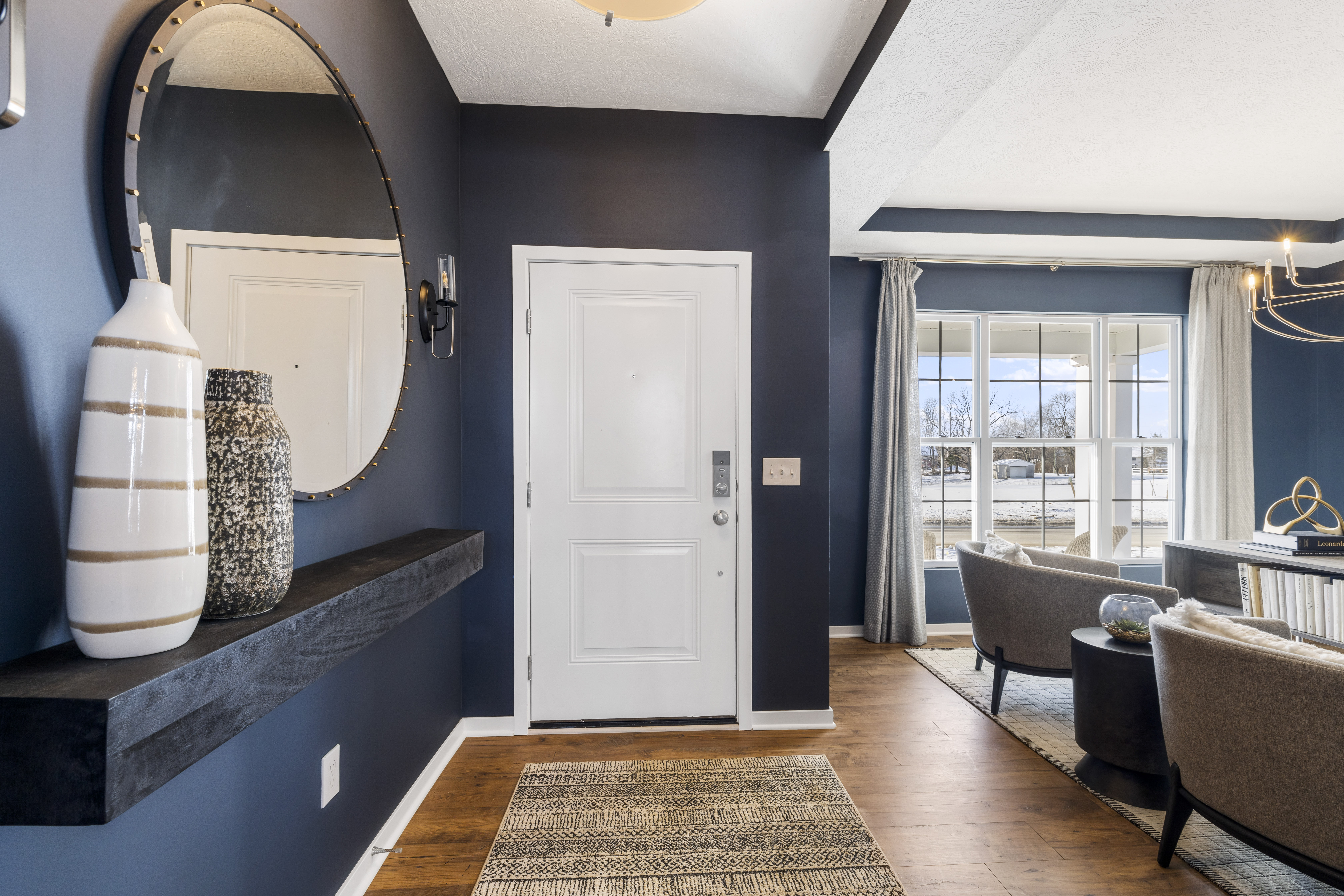 Foyer with blue walls and a large circular mirror hanging