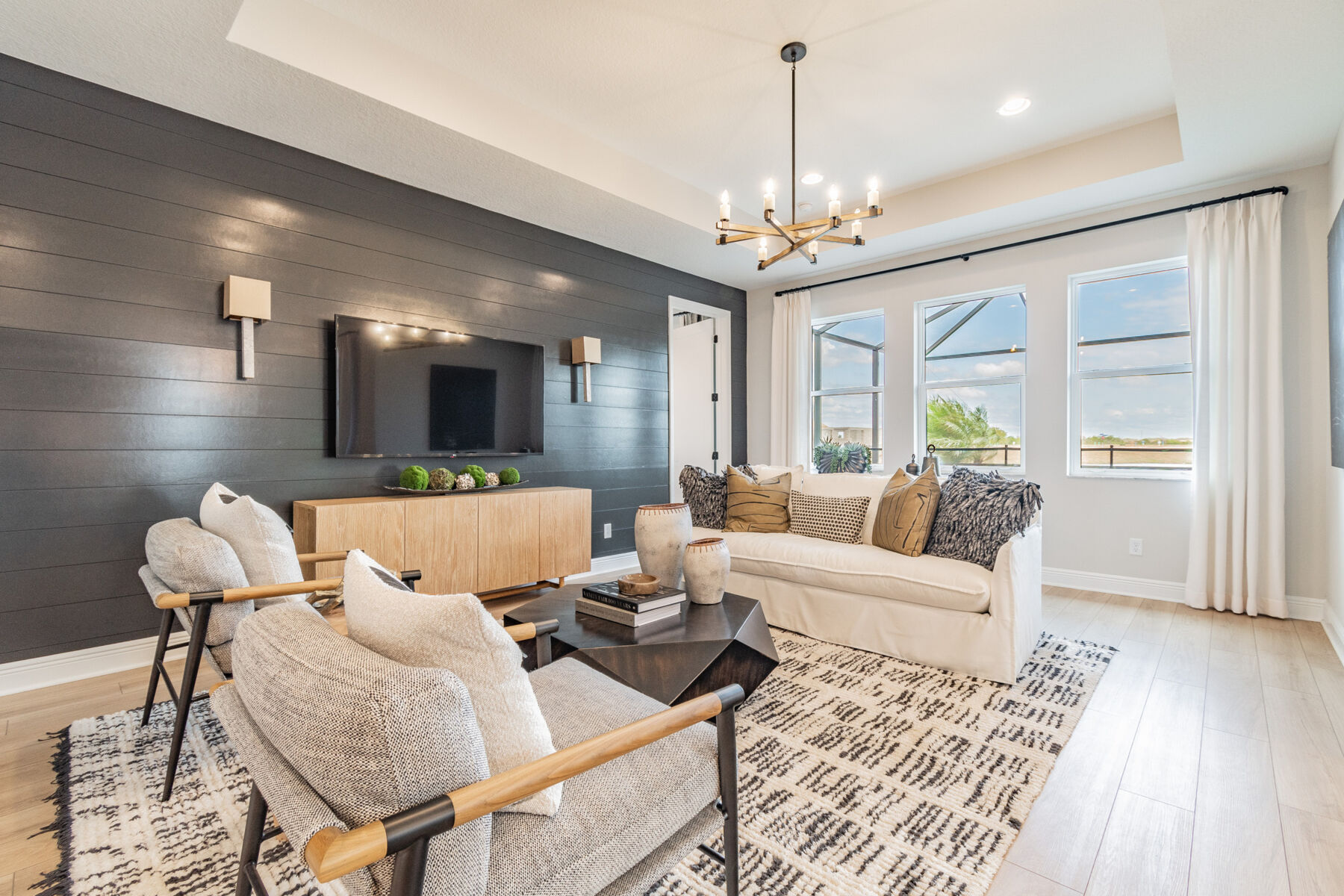 Living room with a tray ceiling, dark brown shiplap wall, and off-white furniture