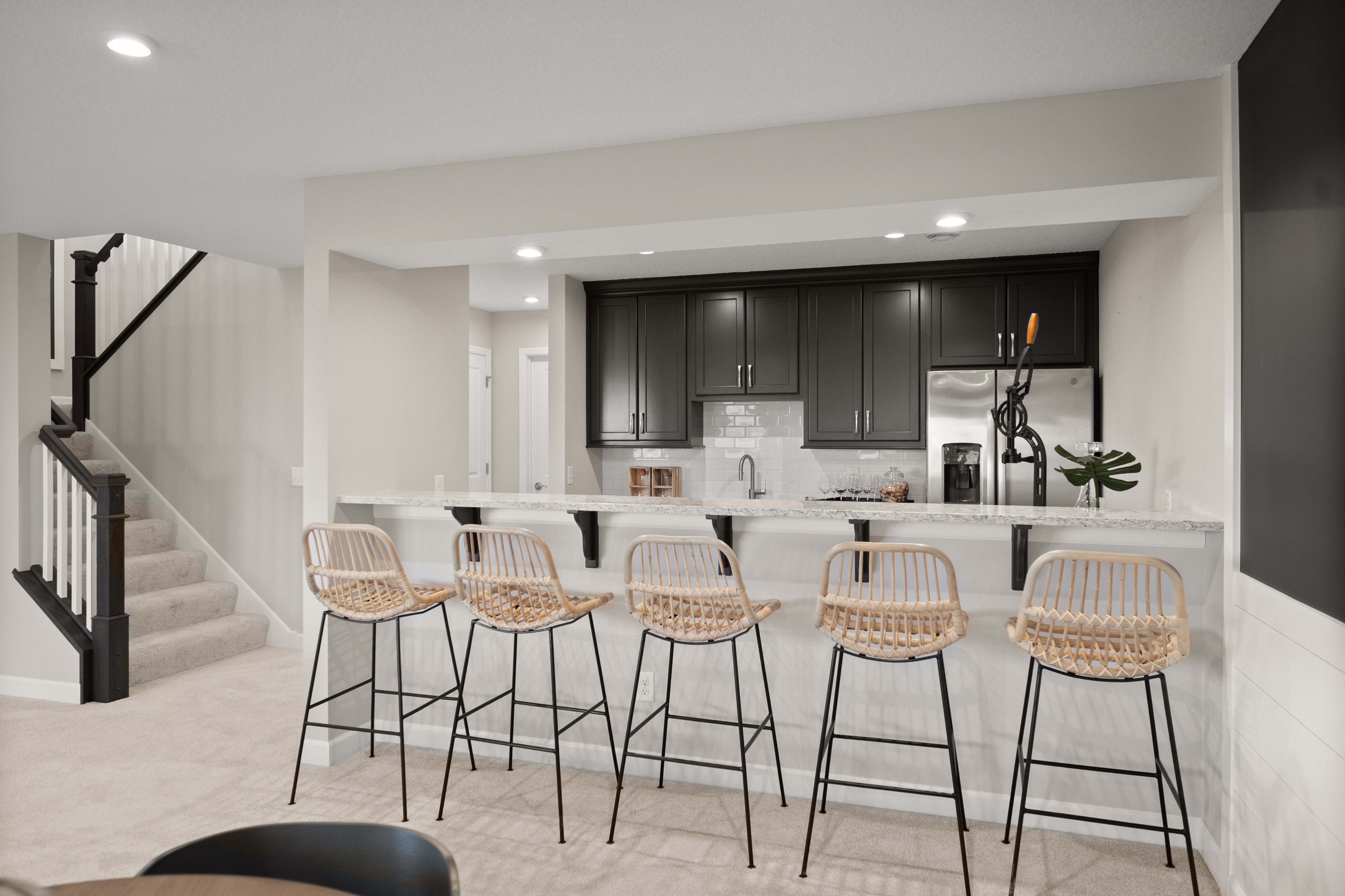 Modern Basement Bar With Grey Countertops and Black Cabinetry