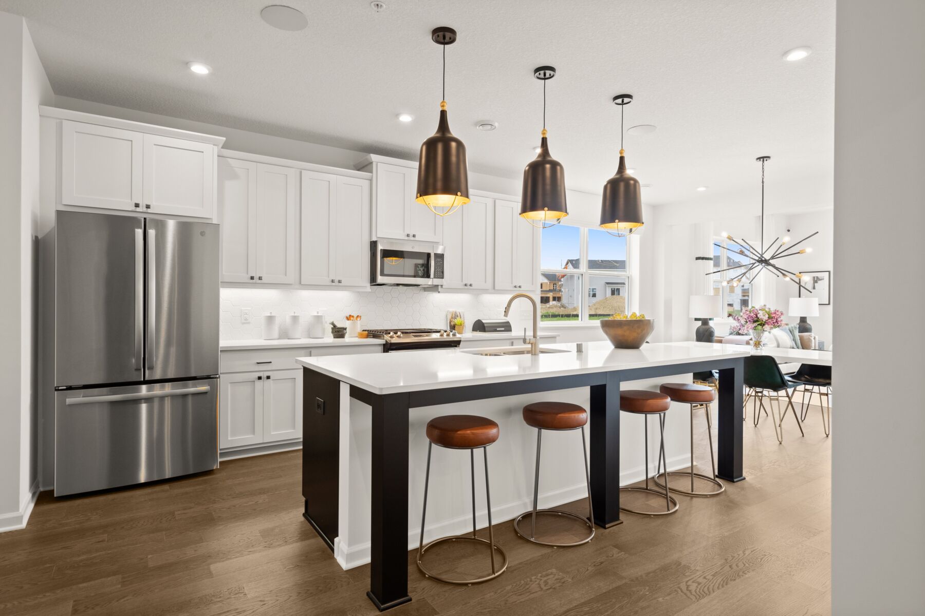 Bright kitchen with white cabinets and countertops and a long island with 4 stools