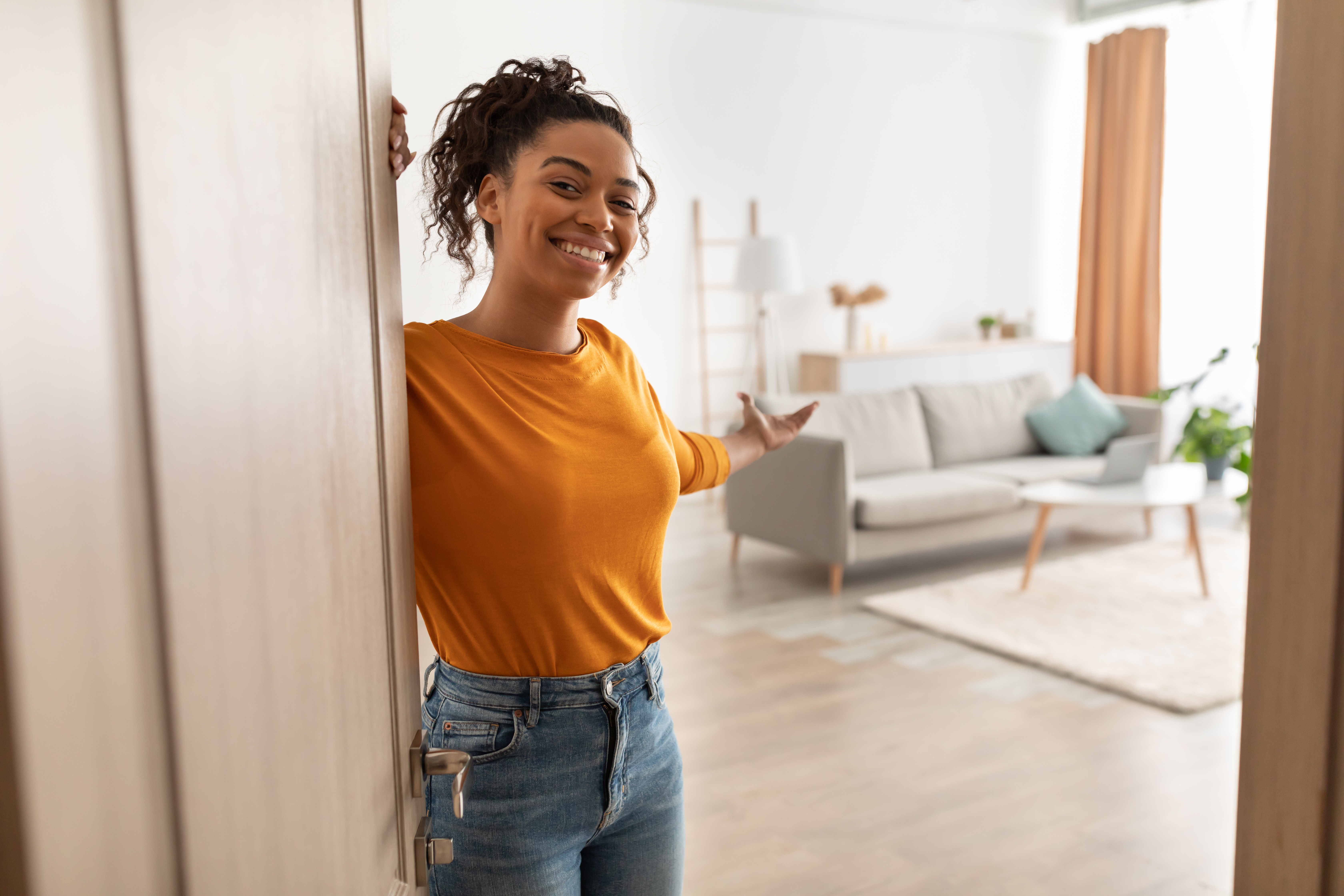 Woman Holding Door Open to Home