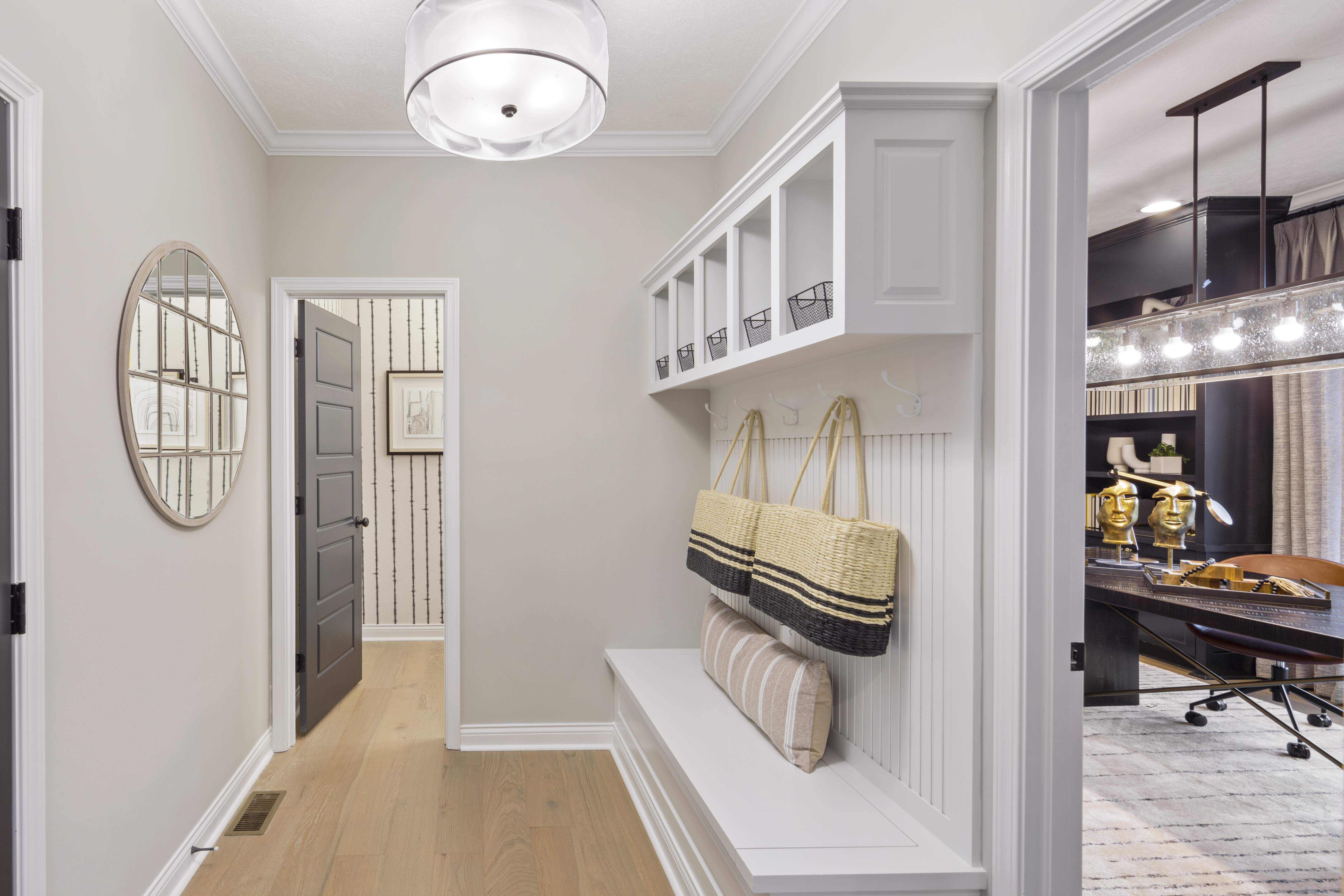 Mud room with a white bench and cubbies and a hanging mirror