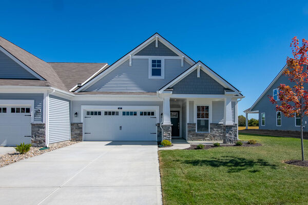 Paired Villa Front Exterior With Gray Siding, Stone, and White Garage Door