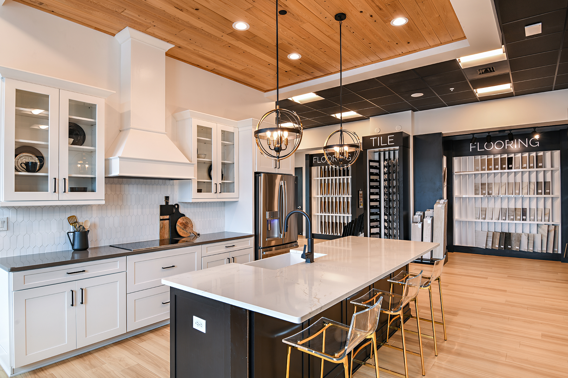 M/I Homes Sarasota Design Studio featuring a kitchen with an island and white cabinets and backsplash; and flooring and tile samples on display