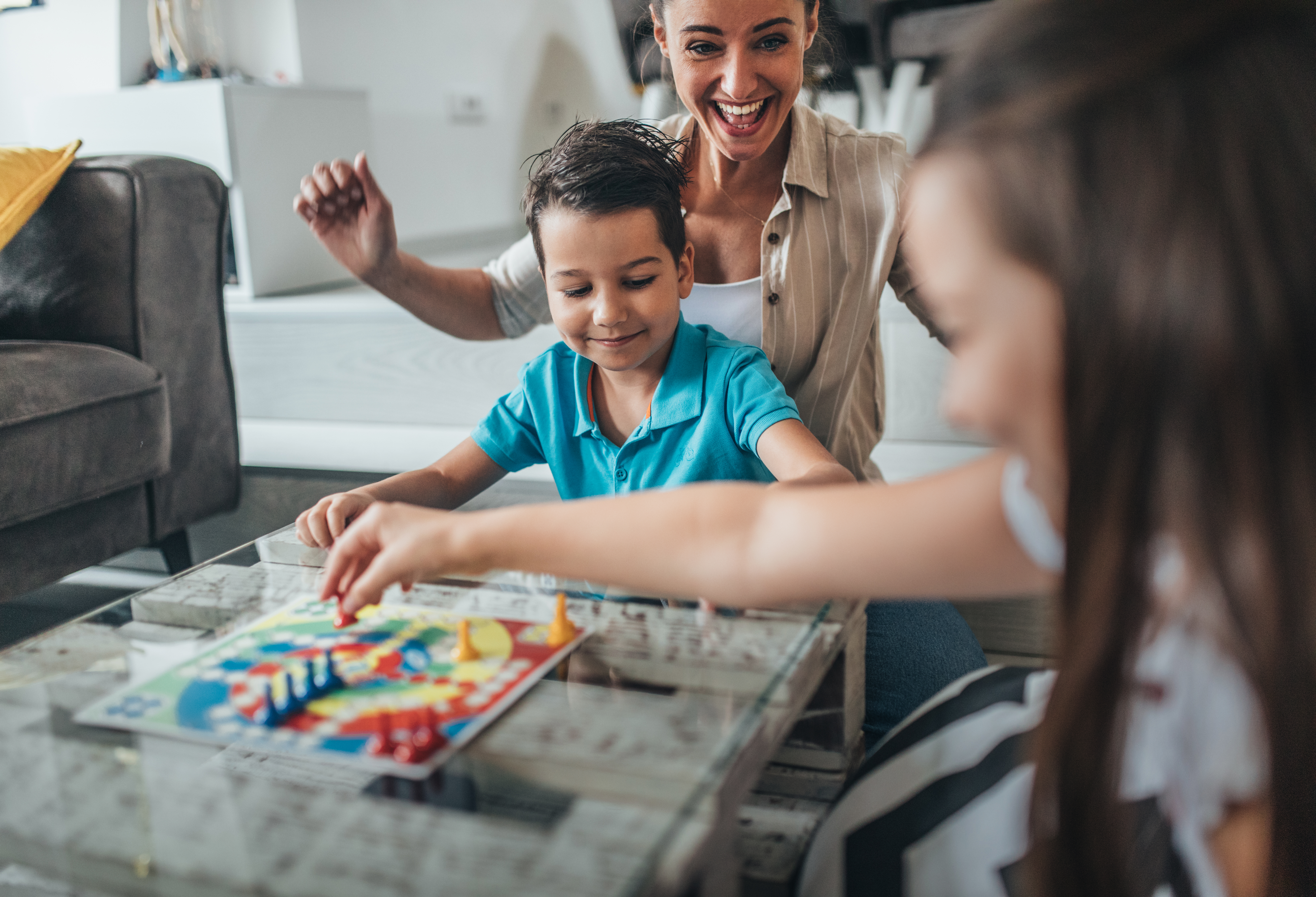 Mom playing board game with young son and daughter