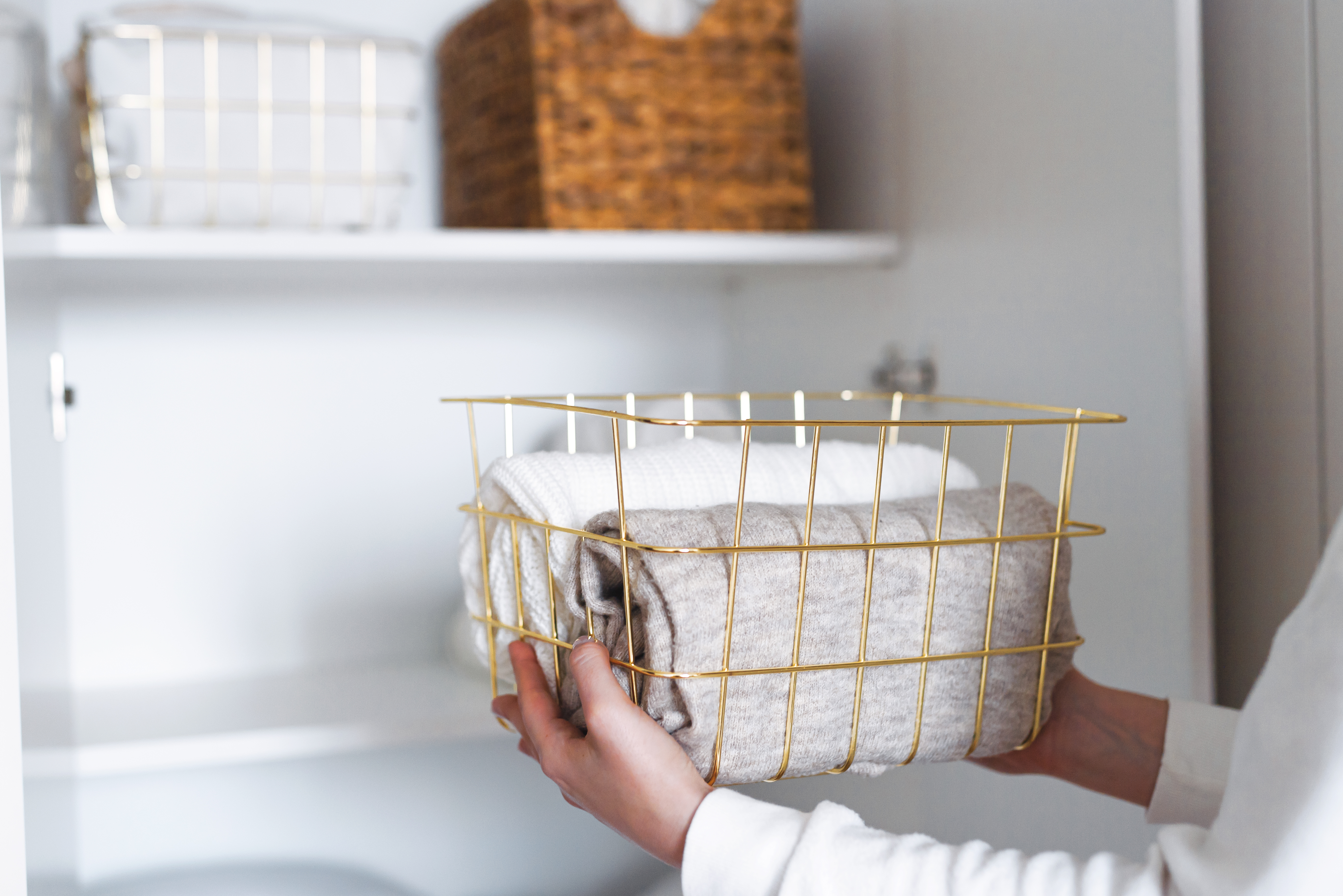 [Person Storing Basket of Towels On A Shelf]