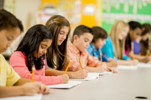 Students writing at a table in class at school